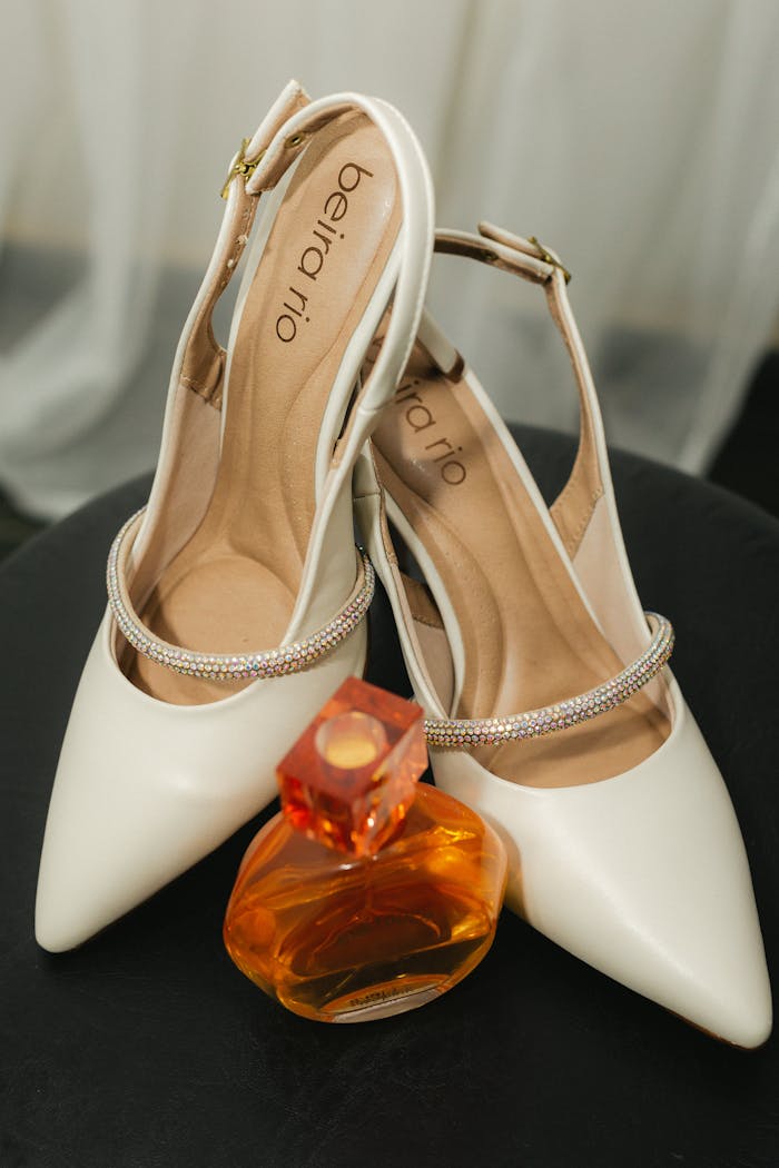 Close-up of stylish white bridal shoes and a perfume bottle, perfect for weddings.